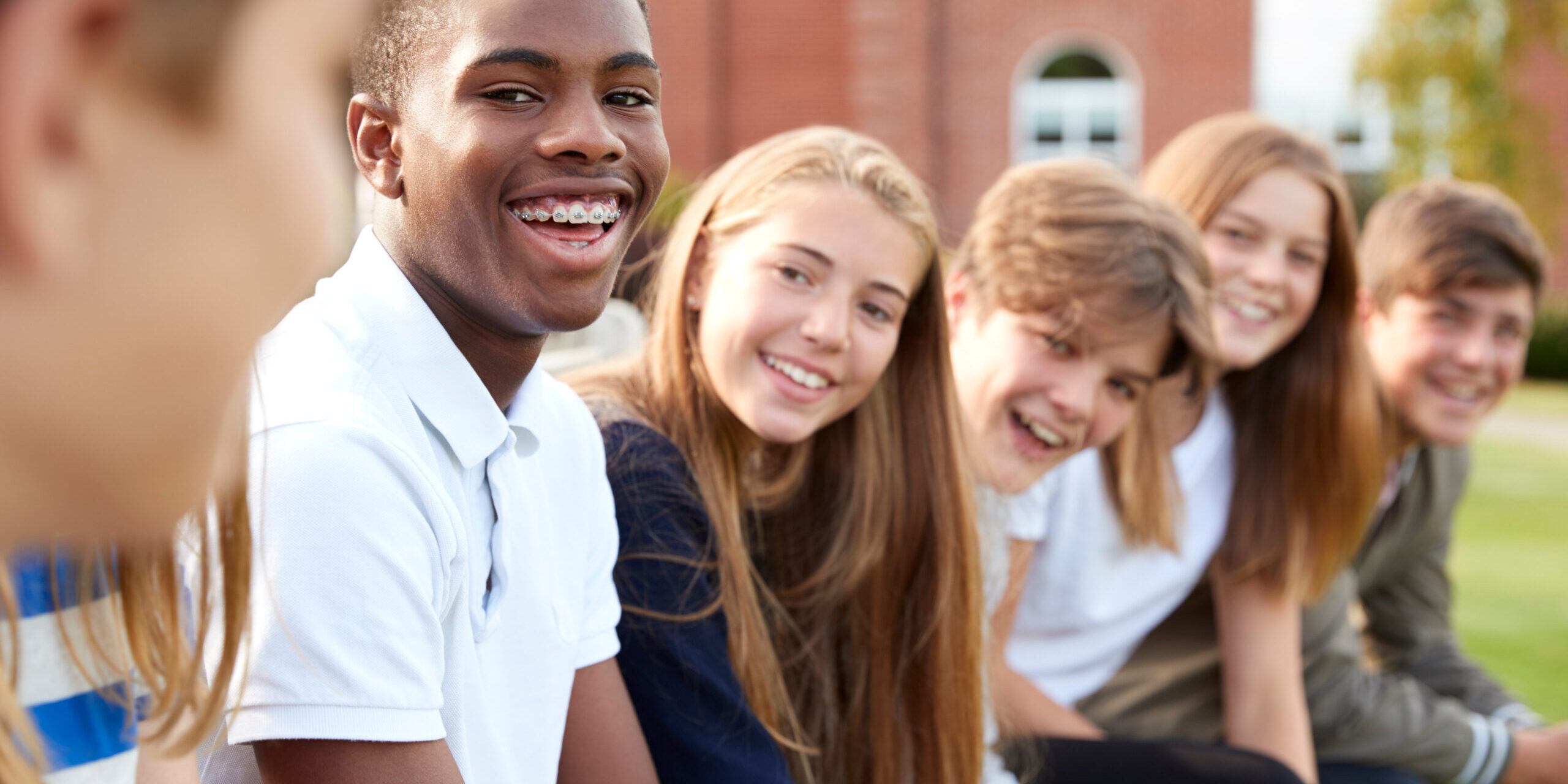 Group Of Teenage Students Sitting Outside School Buildings Students